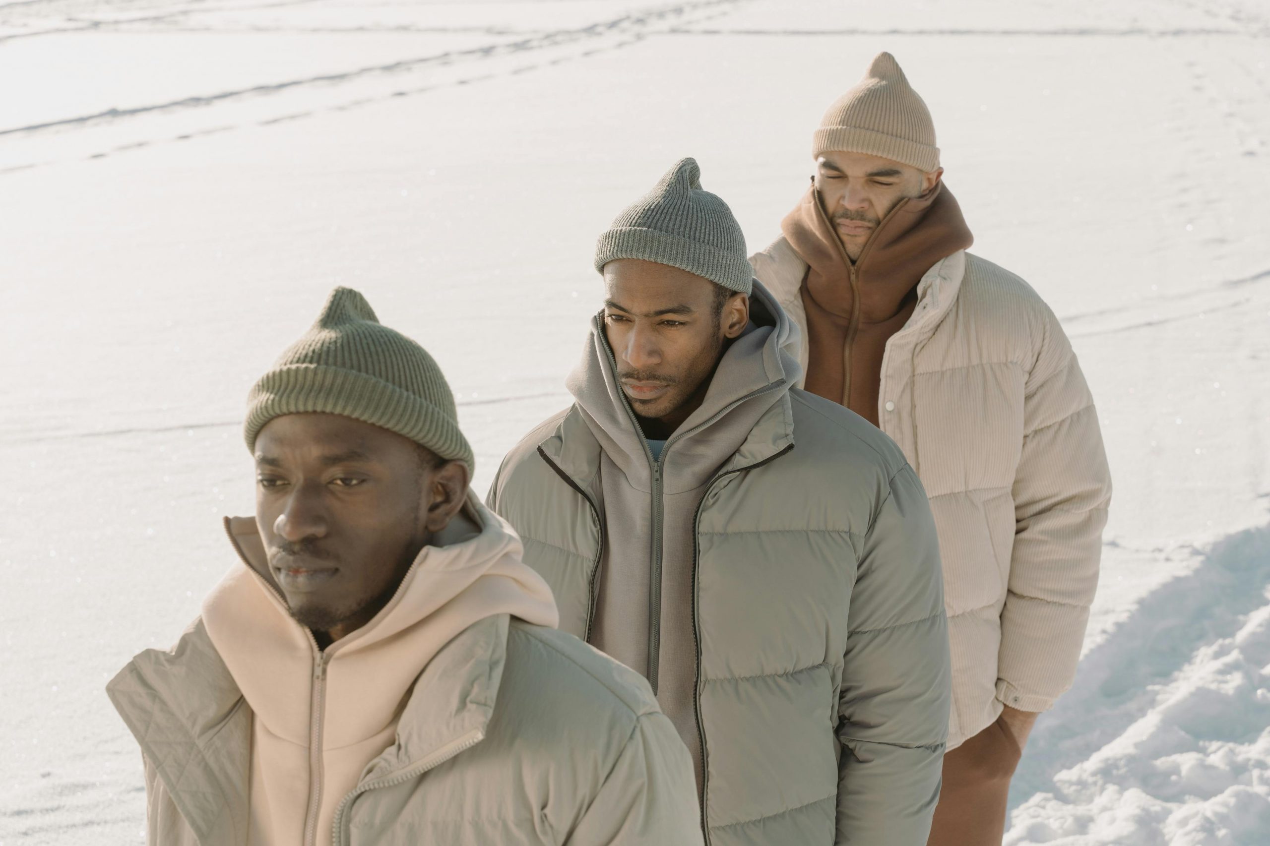 three men wearing down jackets and beanies