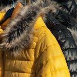 down jackets with fur-trimmed hoods on a rack