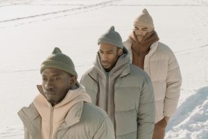 three men wearing down jackets and beanies